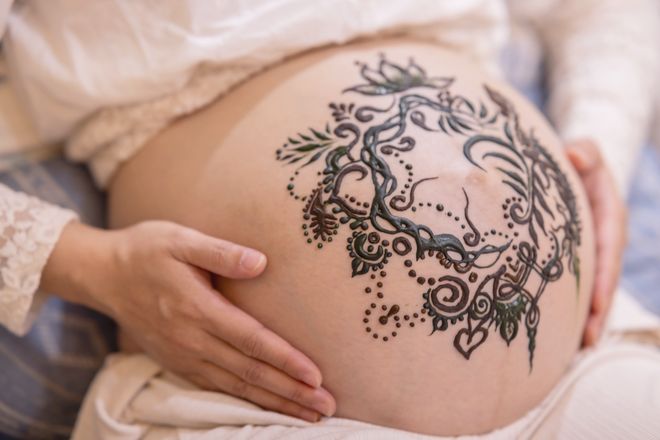 孕婦的肚子上畫著海娜圖騰,一雙手輕輕放著